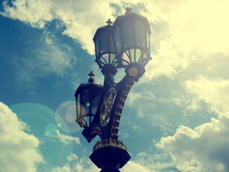 Vintage color toned old street lamp with lens flare on summer skyの写真素材