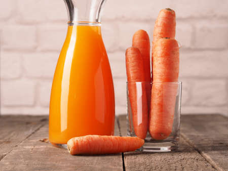 Juice of carrots with organic carrots on a wooden table, healthy food conceptの写真素材