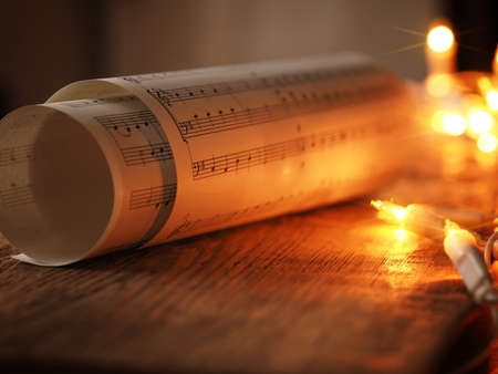 Christmas sheet music on an old wooden table with Christmas lights, romantic scene with selective focusの写真素材