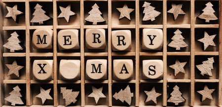 Small wooden dices in a box with the words Merry x-mas, star and tree shape decoration aroundの写真素材