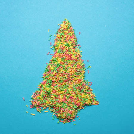 Christmas tree shape of colorful sugar pearls on a blue backgroundの写真素材