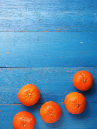 Fresh organic tangerine fruits on a blue weathered wooden tableの写真素材
