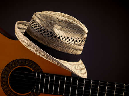 Summer straw hat with an acoustic guitar on a dark backgroundの写真素材