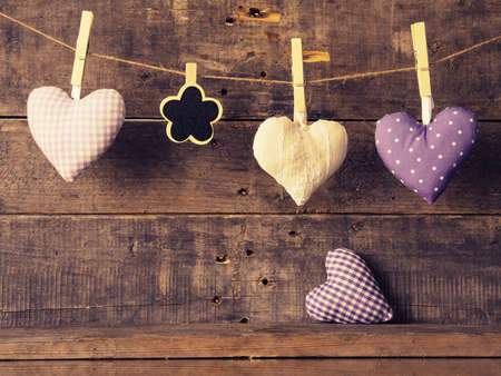 Three fabric heart shapes with a small flower shaped chalkboard on a wooden wall, Valentines Day or Mothers Day conceptの写真素材
