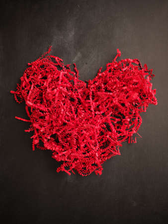 Shredded red paper shaped as a heart shape on a chalkboard, Valentines Day or Mothers Day concept backgroundの写真素材