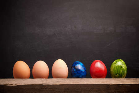Fresh organic Easter eggs in a row on a chalkboard with space for textの写真素材