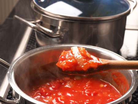 Cooking tasty tomato sauce with garlic onions and spicy herbsの写真素材