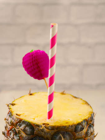 Fresh organic pineapple with a drinking straw on a wooden tableの写真素材
