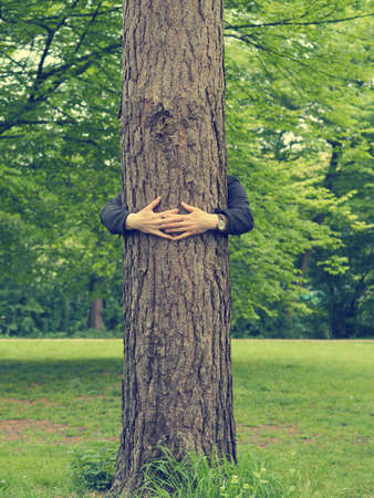 Young man hugs a big tree, environmental or friendship conceptの写真素材