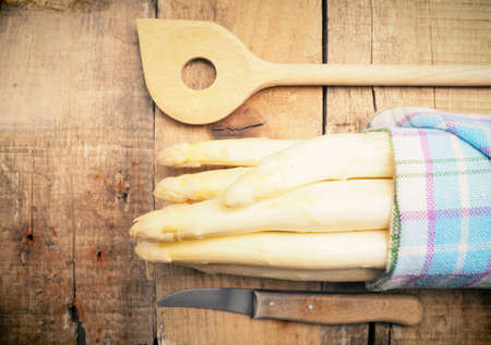 Raw organic white asparagus on a rustic wooden kitchen table, healthy or seasonal foodの写真素材