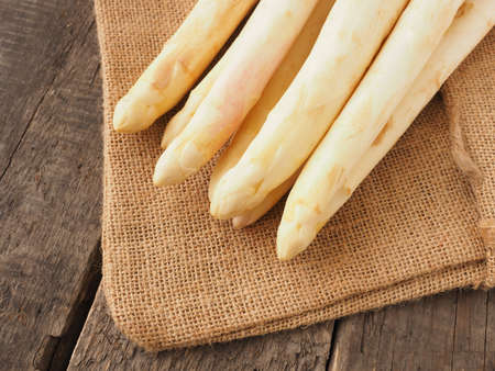 Fresh organic white asparagus on a rustic wooden kitchen table, healthy eating or seasonal food conceptの写真素材
