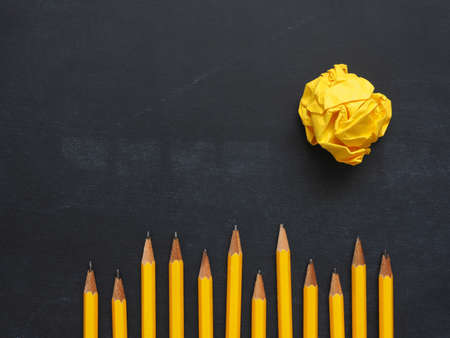 Pencils in a row with yellow crumpled paper on a chalkboard, abstract business or creativity concept