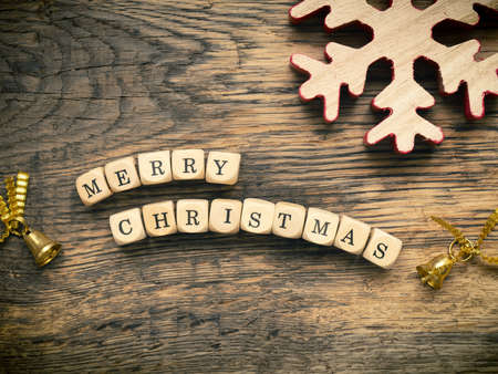 Merry Christmas on small wooden dices with Christmas decoration on a wooden boardの写真素材
