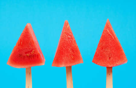 Three watermelon pops on a blue background, refreshment or healthy eating food conceptの写真素材