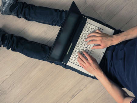 Man with a notebook on a wooden floor, view from aboveの写真素材