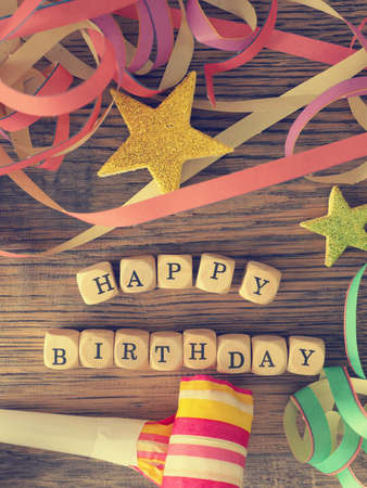 Happy Birthday, wooden dices on a woodent able with birthday decoration, vintage color stylizedの写真素材