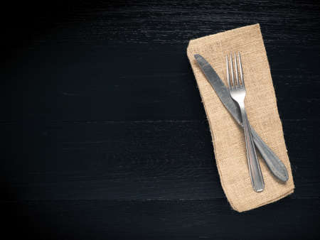 Flatware on a black wooden table with space for textの写真素材