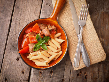 Tasty goulash with whole grain penne in a rustic panの写真素材