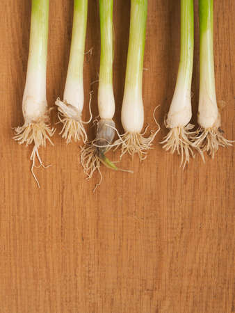 Fresh organic spring onions ona rustic wooden board with space for text