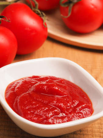 Tasty organic tomato sauce with fresh organic tomatoes on a wooden table, healthy food concept
