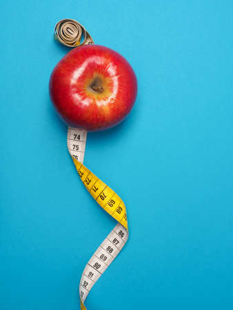 Diet or healthy eating concept with a measuring tape and organic apple