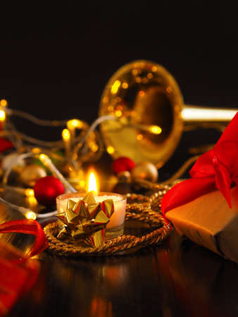 Festive Christmas decoration with one burning candle and brass instrument in the backgroundの写真素材