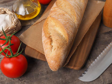 Tasty organic baguette bread with mediterranean ingredients on a rustic kitchen tableの写真素材