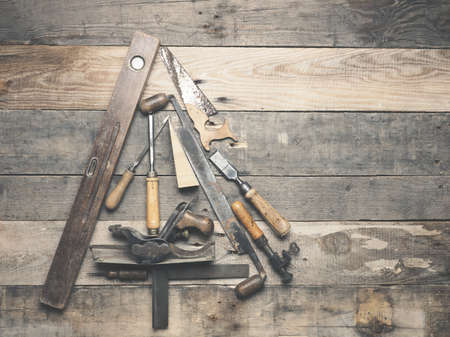 Vintage carpenter tools as a Christmas tree on an old rustic wooden table with space for text on the...