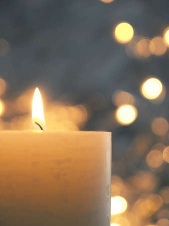 Burning candle with blurred Christmas lightsの写真素材
