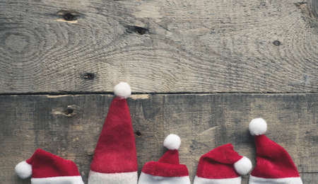 Santa Claus is coming, five hat of Santa on a rustic wooden background with space for textの写真素材