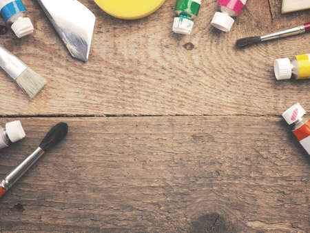 Assortment of different painter utensils on a rustic wooden table with space for your text in the...