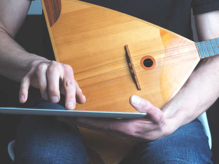 Young musician with a balalaika using a tablet computerの写真素材