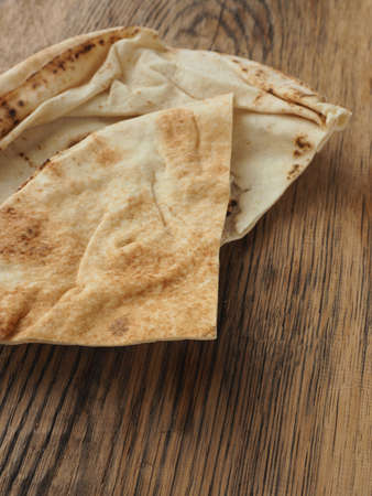 Tasty flatbread stacked on a rustic wooden kitchen table
