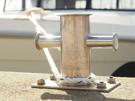 Stainless steel bollard with a rope in a luxury marina