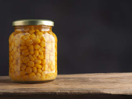 Organic corn in a mason jar on a rustic wooden table with space for text or imageの写真素材