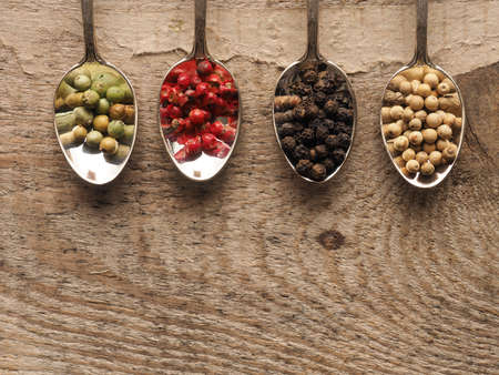 Four vintage spoons with assortment of pepper corns