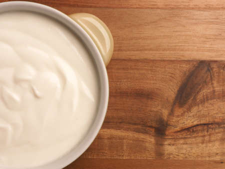Organic yoghurt in a bowl on a wooden table with space for text, view from aboveの写真素材