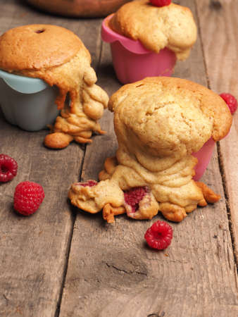 Tasty failed raspberry muffins with organic ingredients on a wooden kitchen tableの写真素材