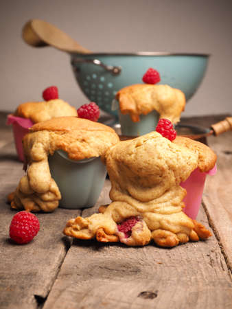 Tasty failed raspberry muffins with organic ingredients on a wooden kitchen tableの写真素材