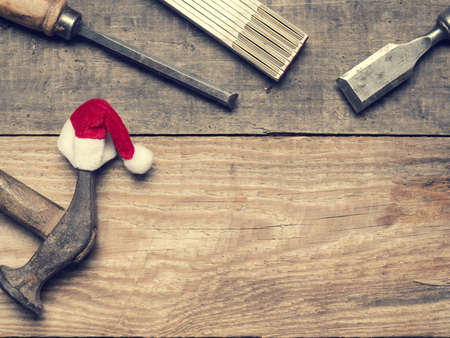 Old used carpenter tools with the hat of Santa, industrial Christmas background with space for text or imageの写真素材