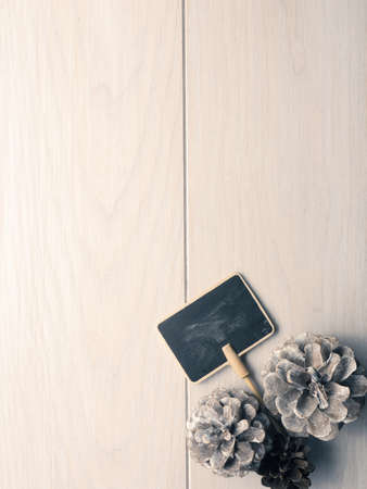 Wooden background with pine pones and a small blackboard