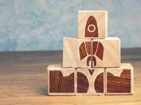 Pyramid of wooden blocks with an abstract rocket, start up concept