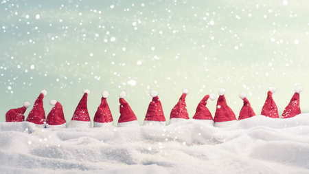 Many hats of Santa in a row with snow, Christmas background, panoramic viewの写真素材