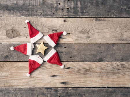 Star shape of hats of Santa with a golden star on a rustic wooden plank with space for text or imageの写真素材