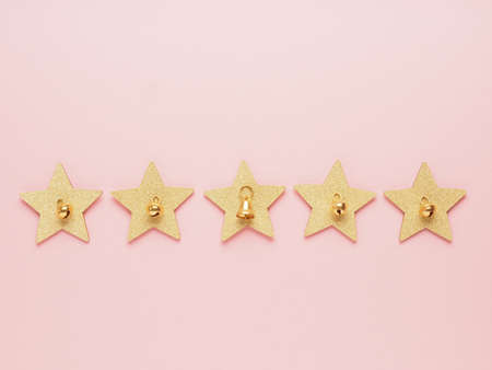 Five golden stars with bells on a pink paper background using as Christmas backdrop or ranking...