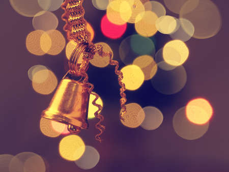 Golden bell on blurred lights background with space for text or imageの写真素材