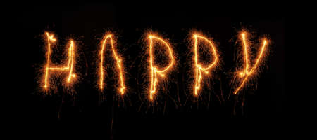 The word HAPPY written with a sparkler on a black backgroundの写真素材