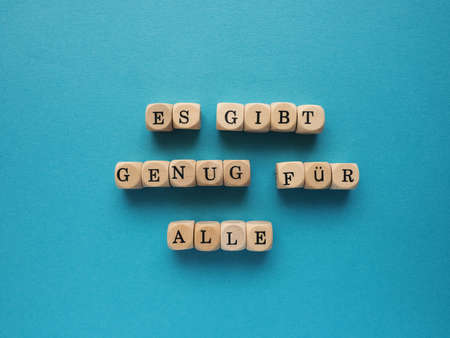German words There is enough for everyone on small wooden blocks, Concept for abundance, sharing or...