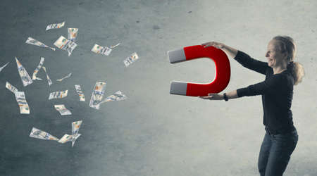 Happy woman with a big magnet attracting money, abundance or wealth concept