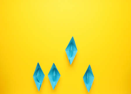 Teamwork business concept with paper boat on yellow background, view from above with space for textの写真素材